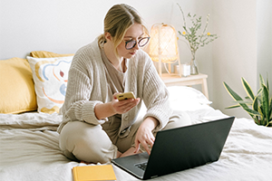 Returns - woman on bed with laptop and phone