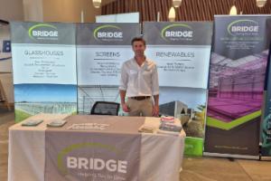 A man standing behind a Bridge Greenhouses trade stall 